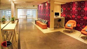 A modern interior with a reception desk, seating area, and a large window. - Mercure Sao Paulo Vila Olimpia (São Paulo)