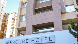 The exterior of the Mercure Hotel with a modern facade, a prominent entrance, and a clear sky. - Mercure Sao Paulo Vila Olimpia (São Paulo)