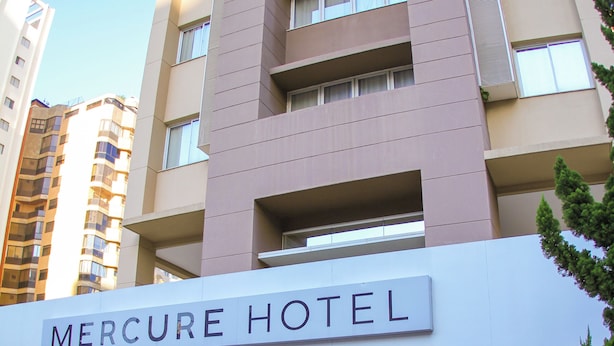 Exterior del hotel Mercure, con fachada moderna, entrada destacada y cielo despejado.