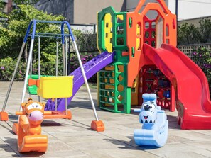 A playground with a swing set, a slide, and two toy animals. - Mercure Sao Paulo Vila Olimpia (São Paulo)