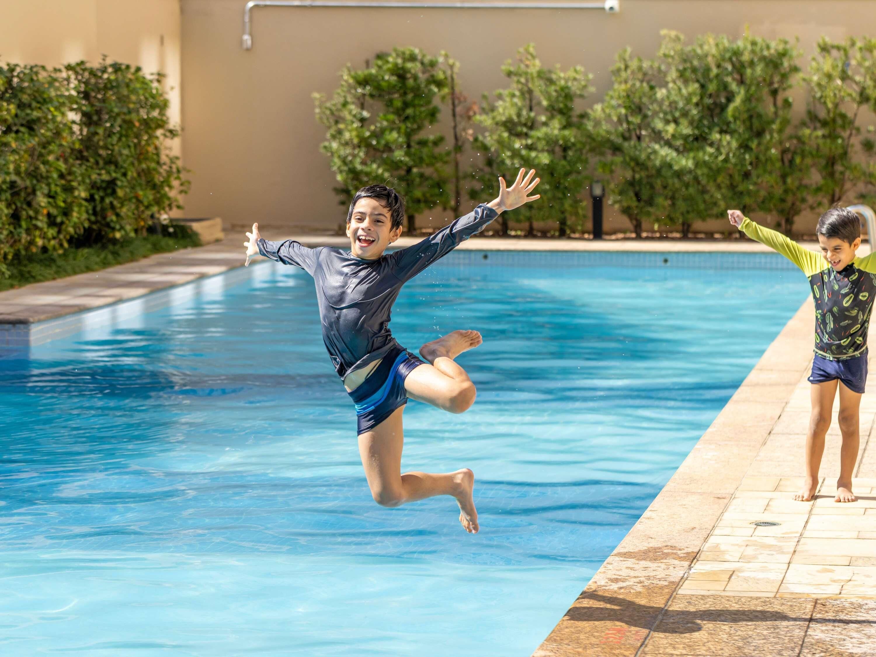Une piscine dans laquelle deux enfants sautent à l’eau.