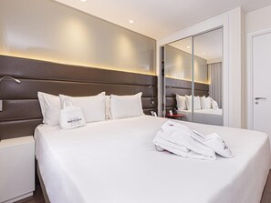 Ein Hotelzimmer mit einem großen Bett, einem Nachttisch, einem Spiegel und einem Kleiderschrank.