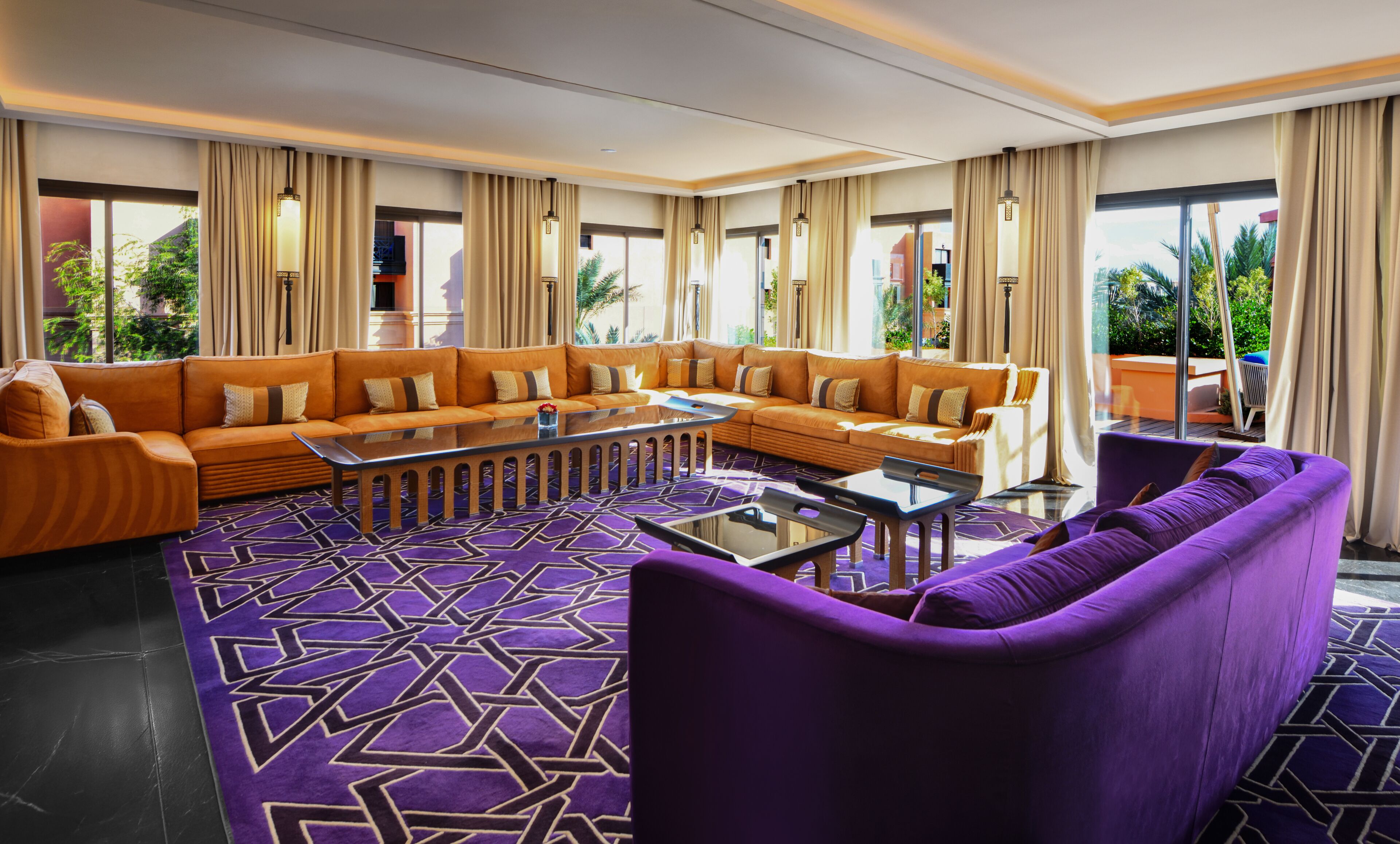 Un hall d’hôtel avec un grand canapé d’angle, une table basse et un fauteuil violet.