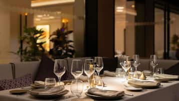A dining table set with multiple wine glasses, plates, and cutlery, indicating a formal dining arrangement.