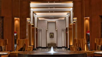 A lobby with a central water feature, flanked by seating areas and a reception desk.