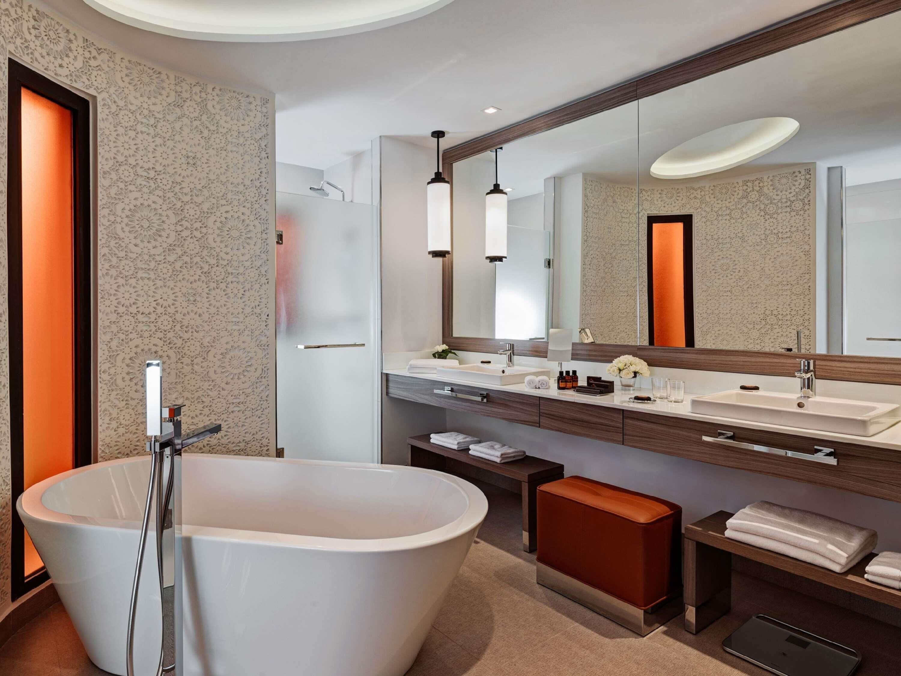 Un baño moderno con una bañera independiente, un espejo grande y un tocador con dos lavamanos.