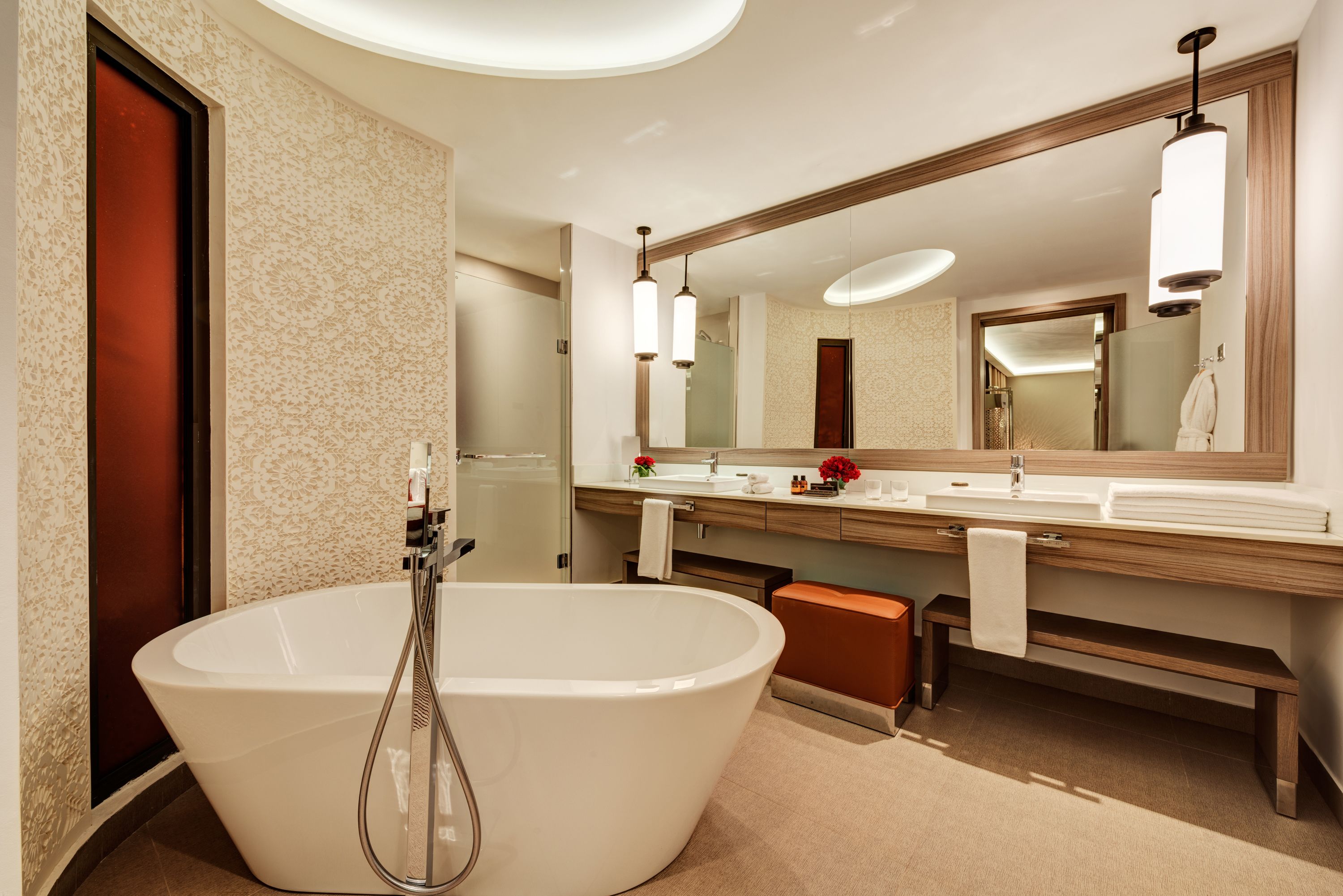 Ein modernes Badezimmer mit einer freistehenden Badewanne, einem großen Spiegel und einem Waschtisch mit Waschbecken und Handtuchhalter.