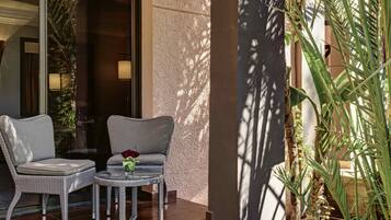 A balcony with wicker furniture, a small table, and a potted plant.