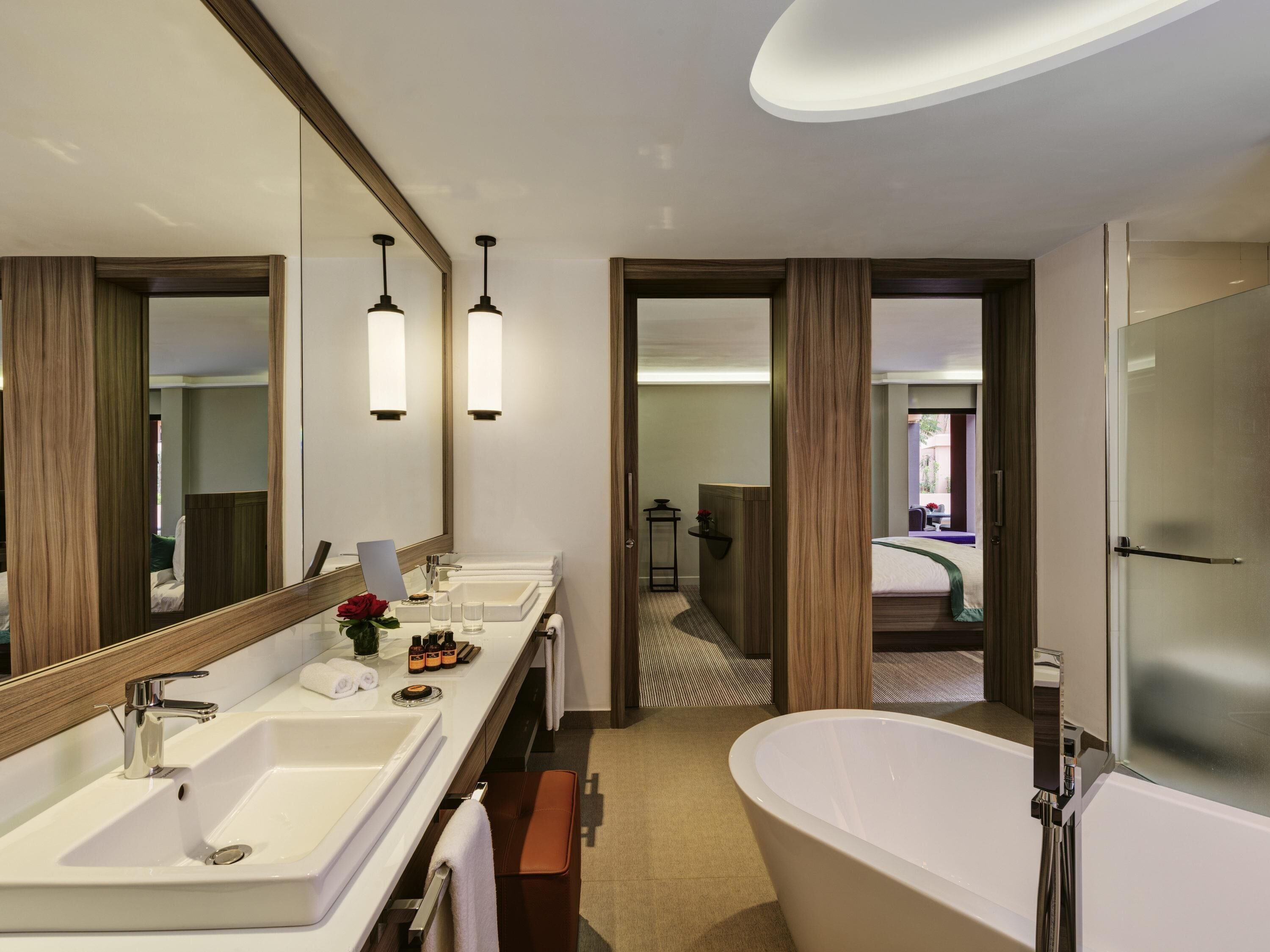 Ein modernes Hotelbad mit einer großzügigen Badewanne, zwei Waschbecken, einem Spiegel und einem Schminktisch.