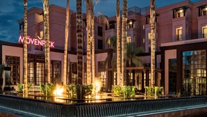 Un hotel con fachada moderna, palmeras y una entrada bien iluminada.