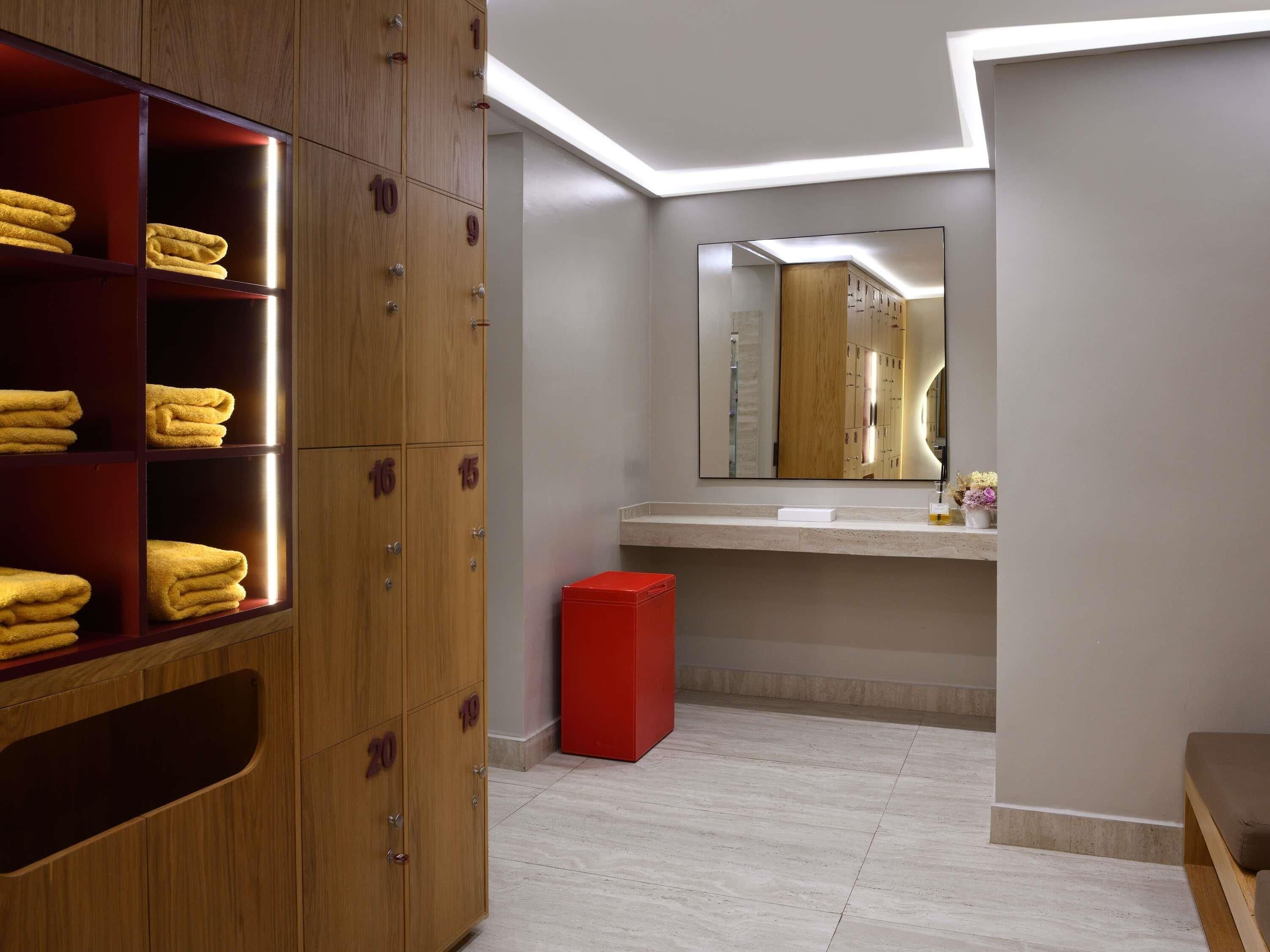 Un baño moderno con muebles de madera, un espejo y un bote de basura rojo.
