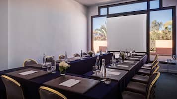 A conference room with a long table, chairs, water bottles, and a vase of flowers.