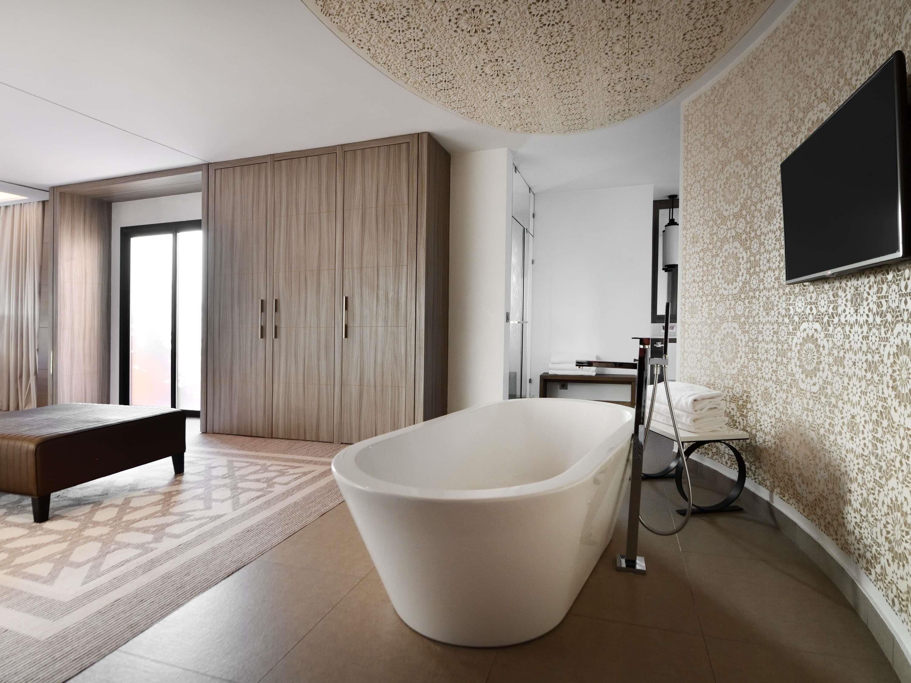 Une salle de bain moderne avec une baignoire sur pieds, une douche et un téléviseur fixé au mur.