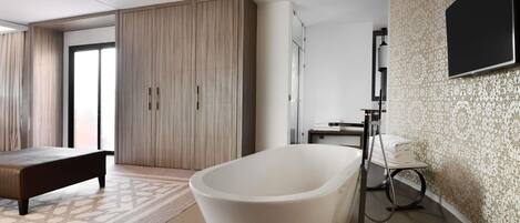 A modern bathroom with a freestanding bathtub, a shower, and a wall-mounted TV.