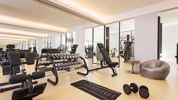 A modern gym with various exercise equipment, including dumbbells, a treadmill, and weight machines.
