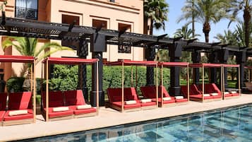 A poolside area with red lounge chairs and a pergola structure.
