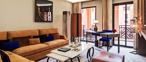 A hotel room with a sofa, a small table, a chair, a lamp, and a view of the outside.