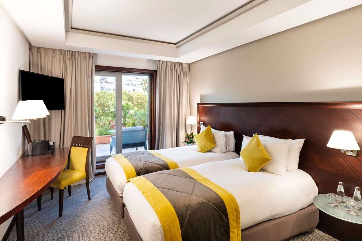 A hotel room with two beds, a desk, and a chair.