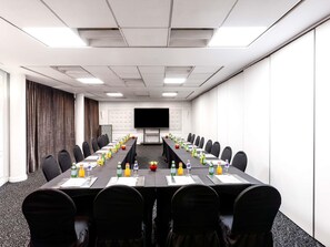 A conference room with a long table, chairs, a large screen, and beverages. - Le Diwan Hotel Rabat - MGallery Collection (Rabat)