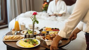 A breakfast tray with various dishes, a rose, and a person serving food in a hotel room. - Le Diwan Hotel Rabat - MGallery Collection (Rabat)