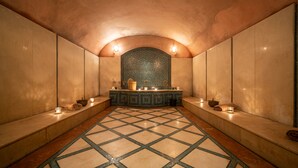 A spa room with a tiled floor, benches, a counter with candles, and a decorative wall. - Le Diwan Hotel Rabat - MGallery Collection (Rabat)