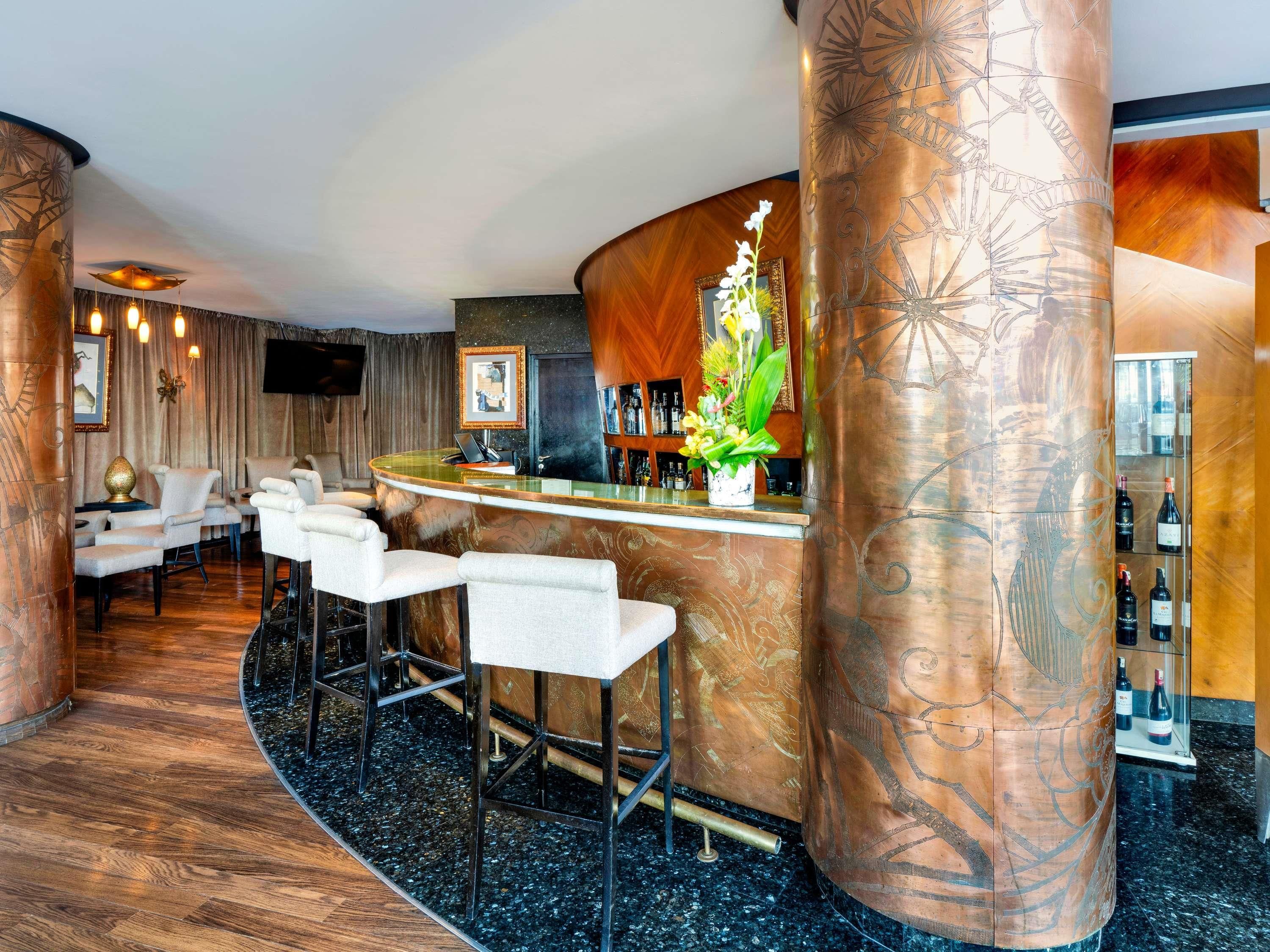 A bar area with a curved counter, bar stools, and a decorative plant.