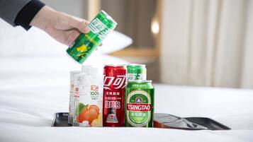 A hand holding a green can, with other beverage cans and a carton on a tray.
