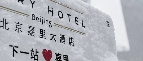 A snow-covered sign for Beijing Hotel with Chinese characters and a heart symbol indicating a location.