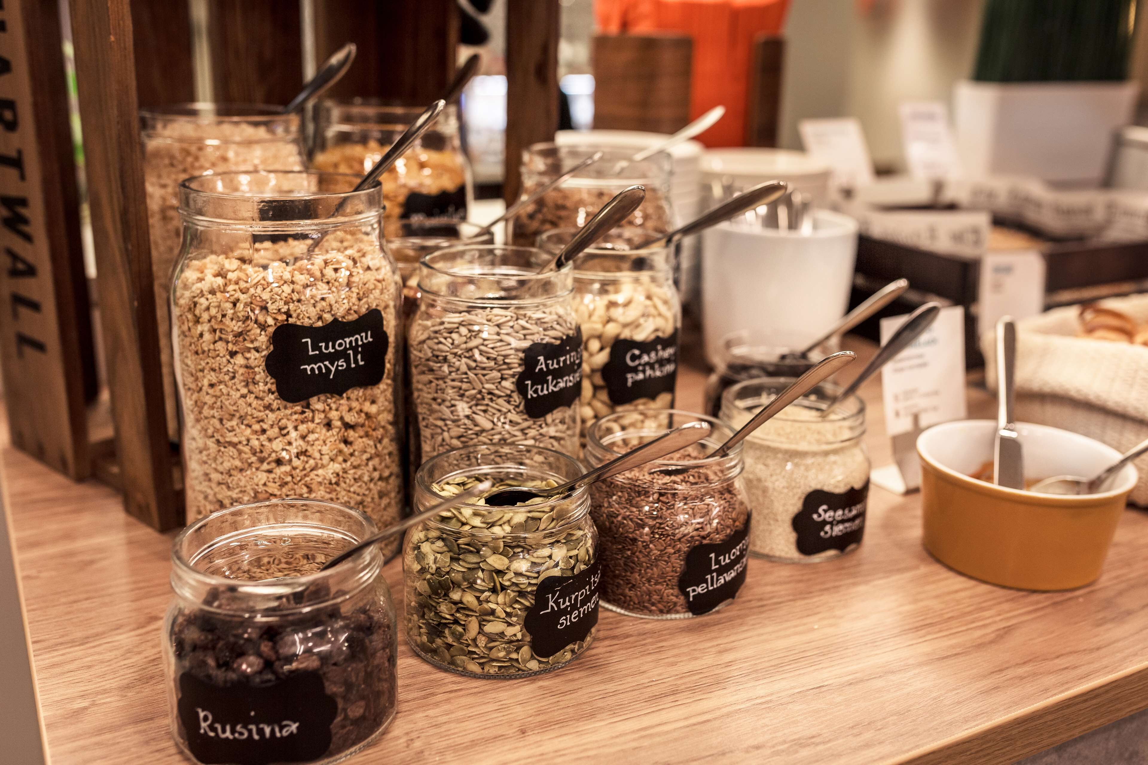 A variety of jars with labels indicating different types of seeds and grains, such as "Luomu mysil" and "Kurkitsa sieemen."