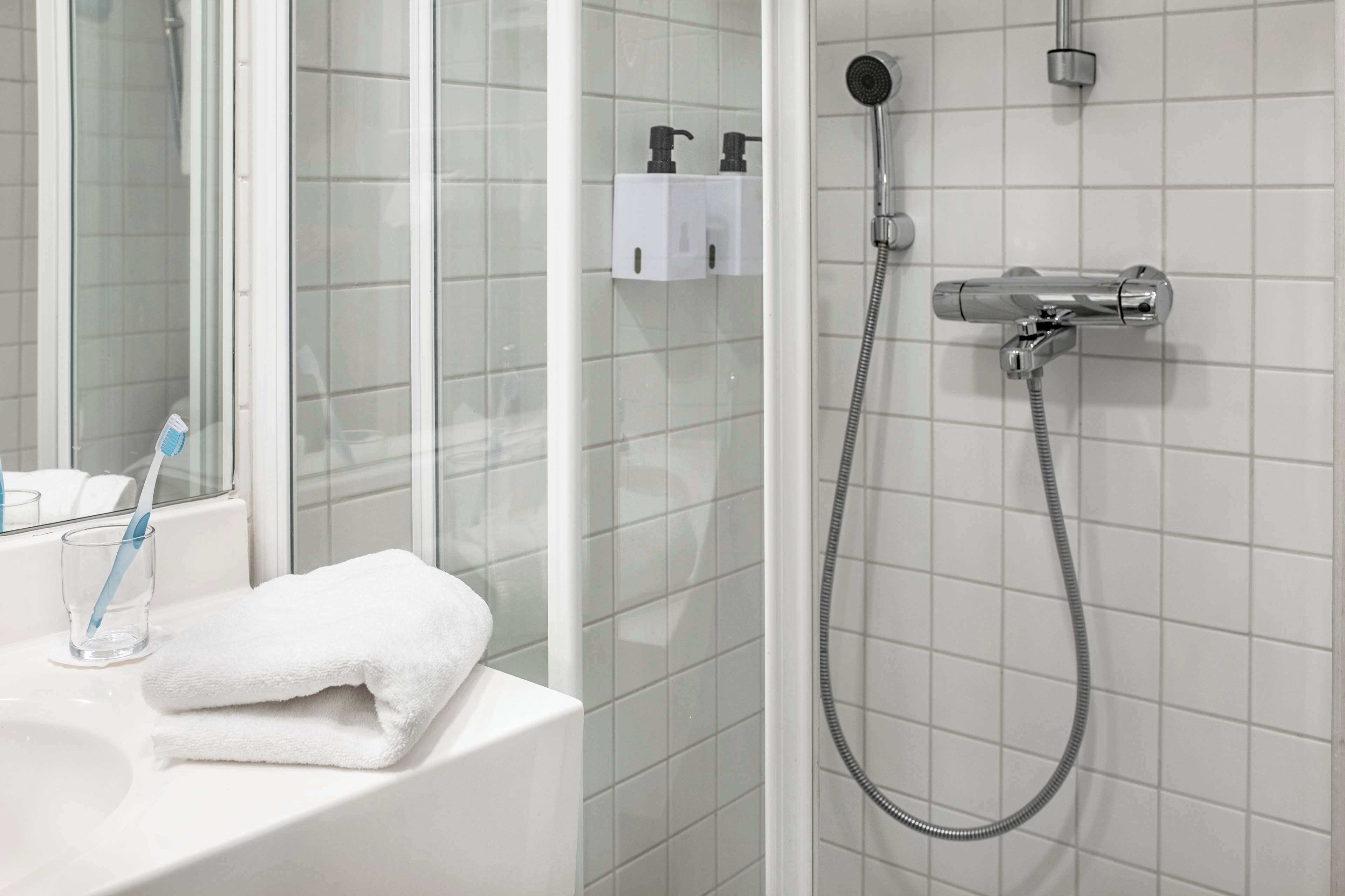 A bathroom with a glass shower enclosure, a white sink, and a towel.