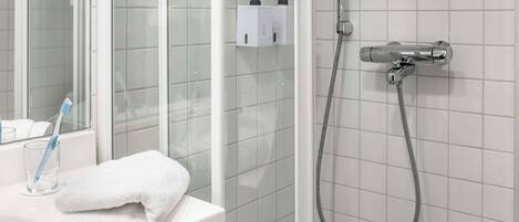 A bathroom with a glass shower enclosure, a white sink, and a towel.