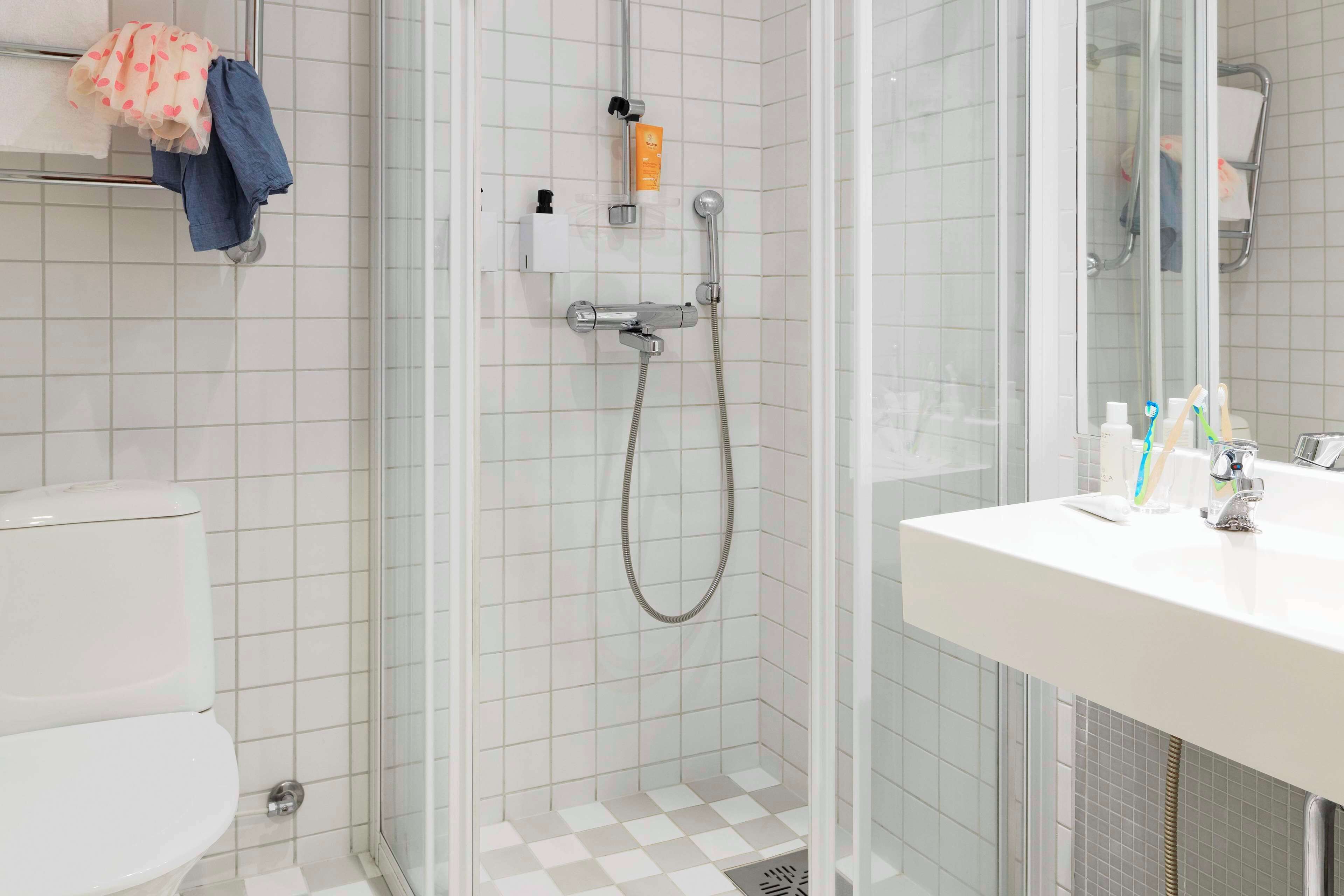 A modern bathroom with a glass-enclosed shower, a white sink with toiletries, and a toilet.