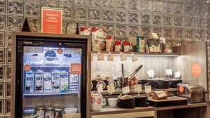 A refrigerated display with various dairy products and a counter with jars and a toaster. - Scandic Plaza Turku (Turku)