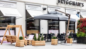 An outdoor seating area with wooden planters and a swing set in front of Bryggman's restaurant. - Scandic Plaza Turku (Turku)