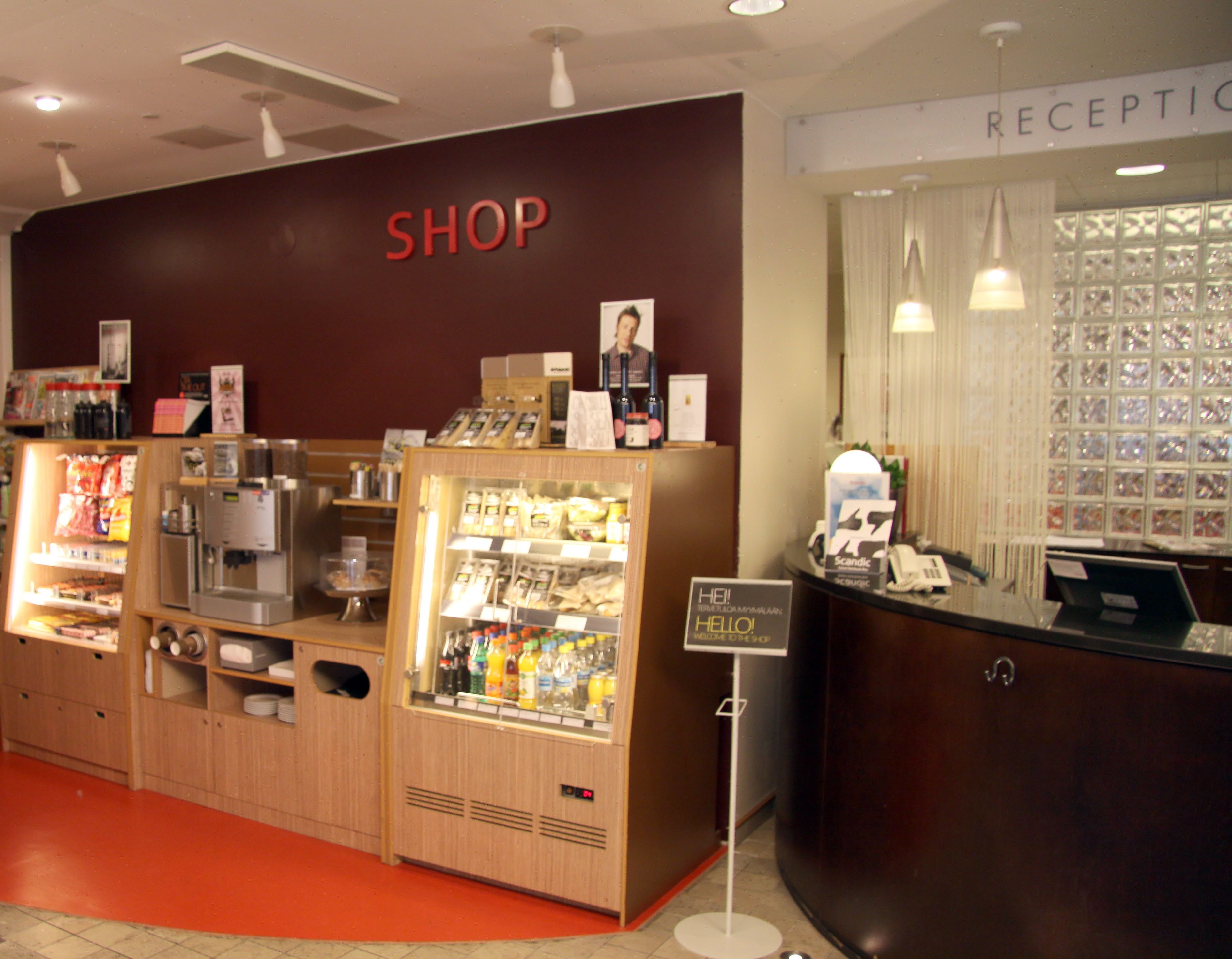 Zona comercial con mostrador de recepción, máquina de café y vitrina refrigerada.