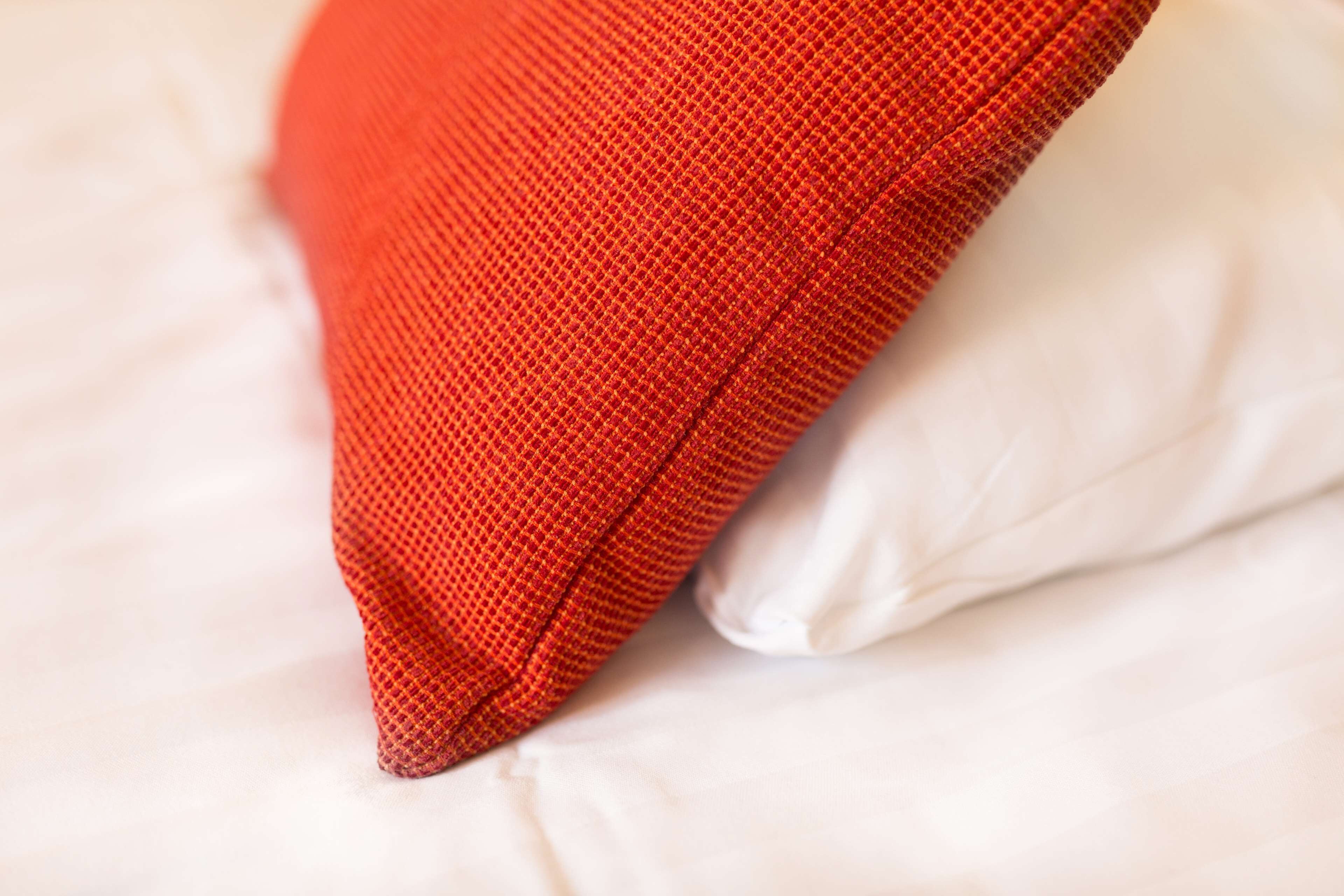 A close-up of a red fabric object, possibly a pillow, resting on a white surface.