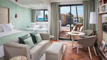 A hotel room with a bed, a sofa, a small table, and a chair. There is a balcony with a table and chairs outside.