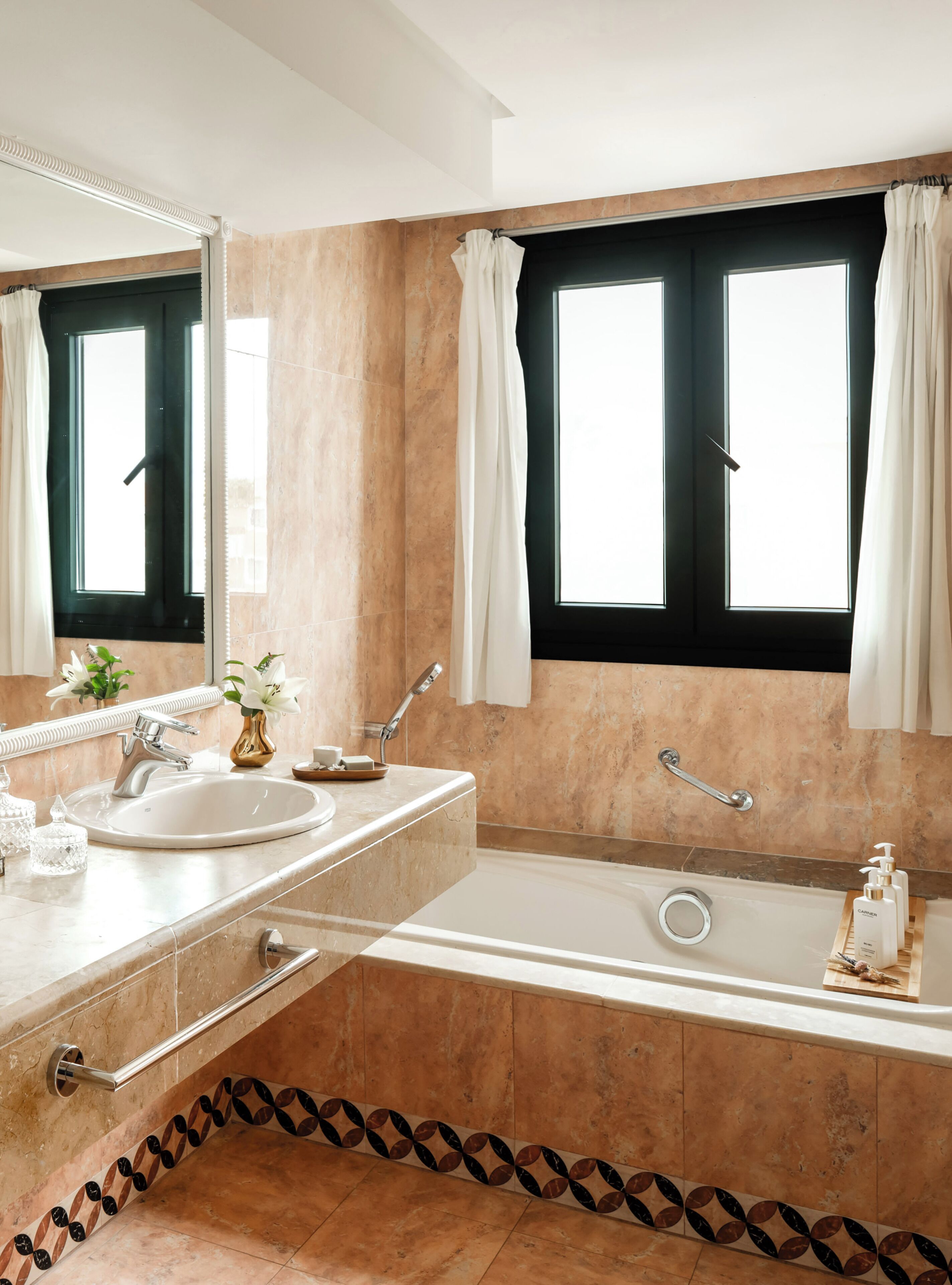 A bathroom with a bathtub, a sink, a mirror, and two windows with curtains.