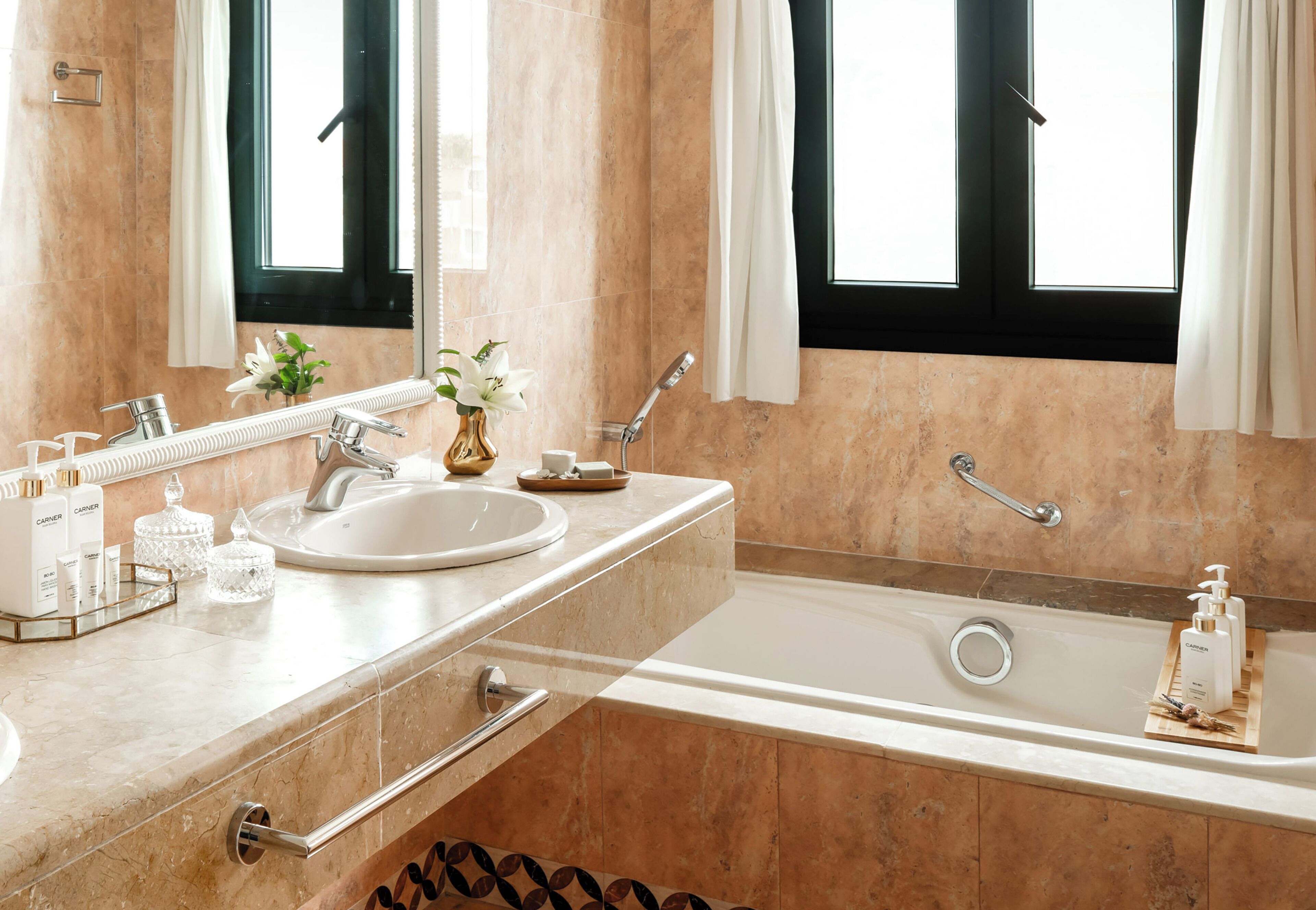 Un baño con bañera, lavamanos, espejo y ventana con cortinas.