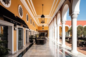 A corridor with a yellow wall, black-framed windows, and a central hanging light fixture.