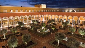 A courtyard with multiple seating areas and a central fountain, surrounded by trees and pathways. - Palacio de Sancti Petri, a Gran Meliá - The Leading Hotels of the World (Chiclana de la Frontera)