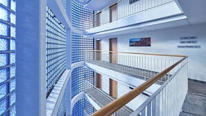 A multi-level interior with glass walls, railings, and directional signs. - Lindner Hotel Cologne Am Dom, part of JdV by Hyatt (Cologne)