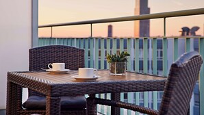 A balcony with wicker furniture, a white cup, and a potted plant. - Lindner Hotel Cologne Am Dom, part of JdV by Hyatt (Cologne)