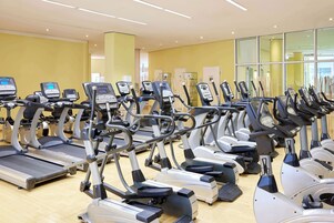 A gym with multiple treadmills and elliptical machines arranged in rows.