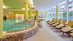 A swimming pool with a tiled edge, sun loungers, and large windows. - Lindner Hotel Cologne Am Dom, part of JdV by Hyatt (Cologne)