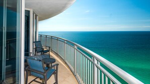 A balcony with two chairs and a table, overlooking a clear blue sea.