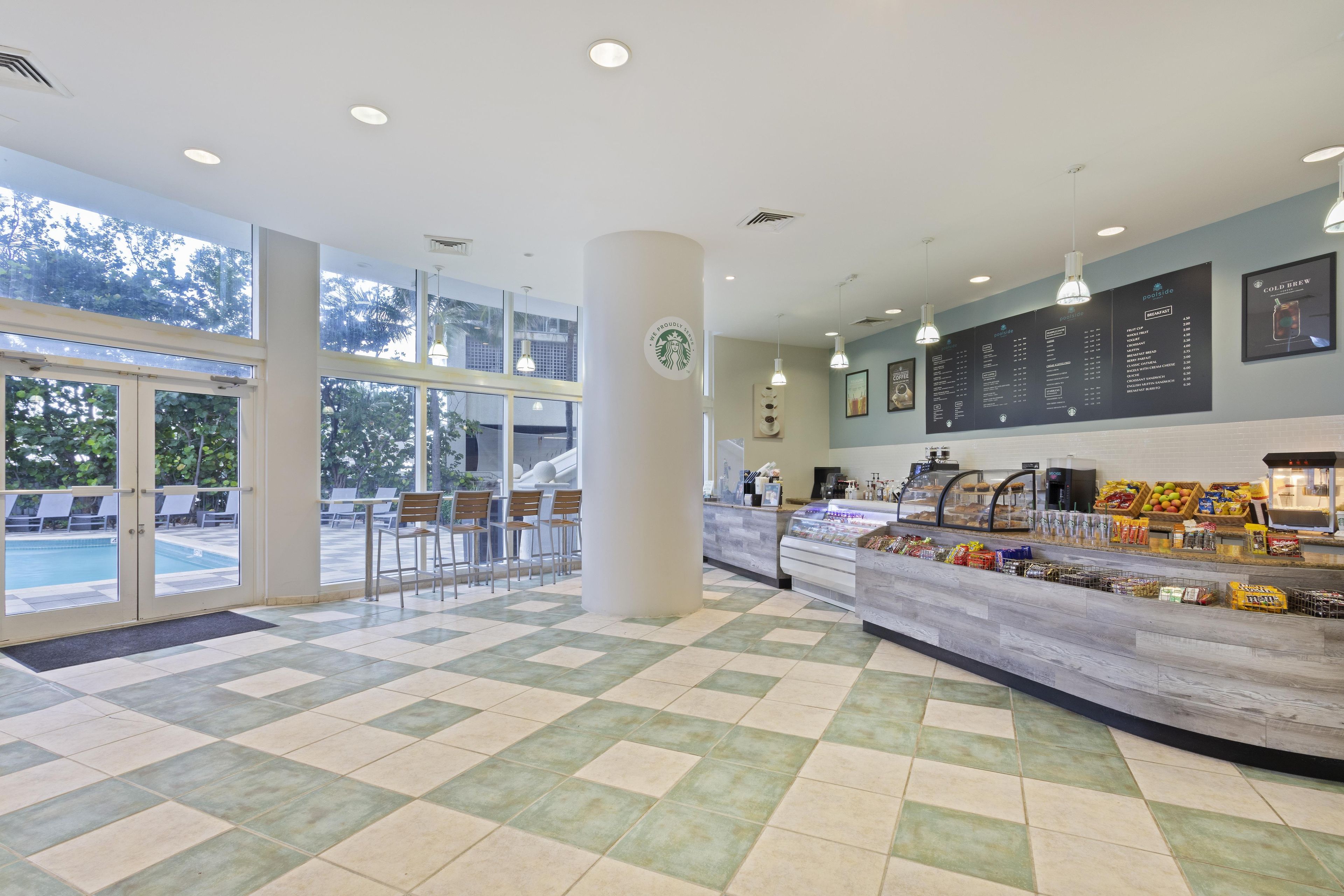 Una cafetería Starbucks con vista a una piscina, suelo a cuadros y un menú.