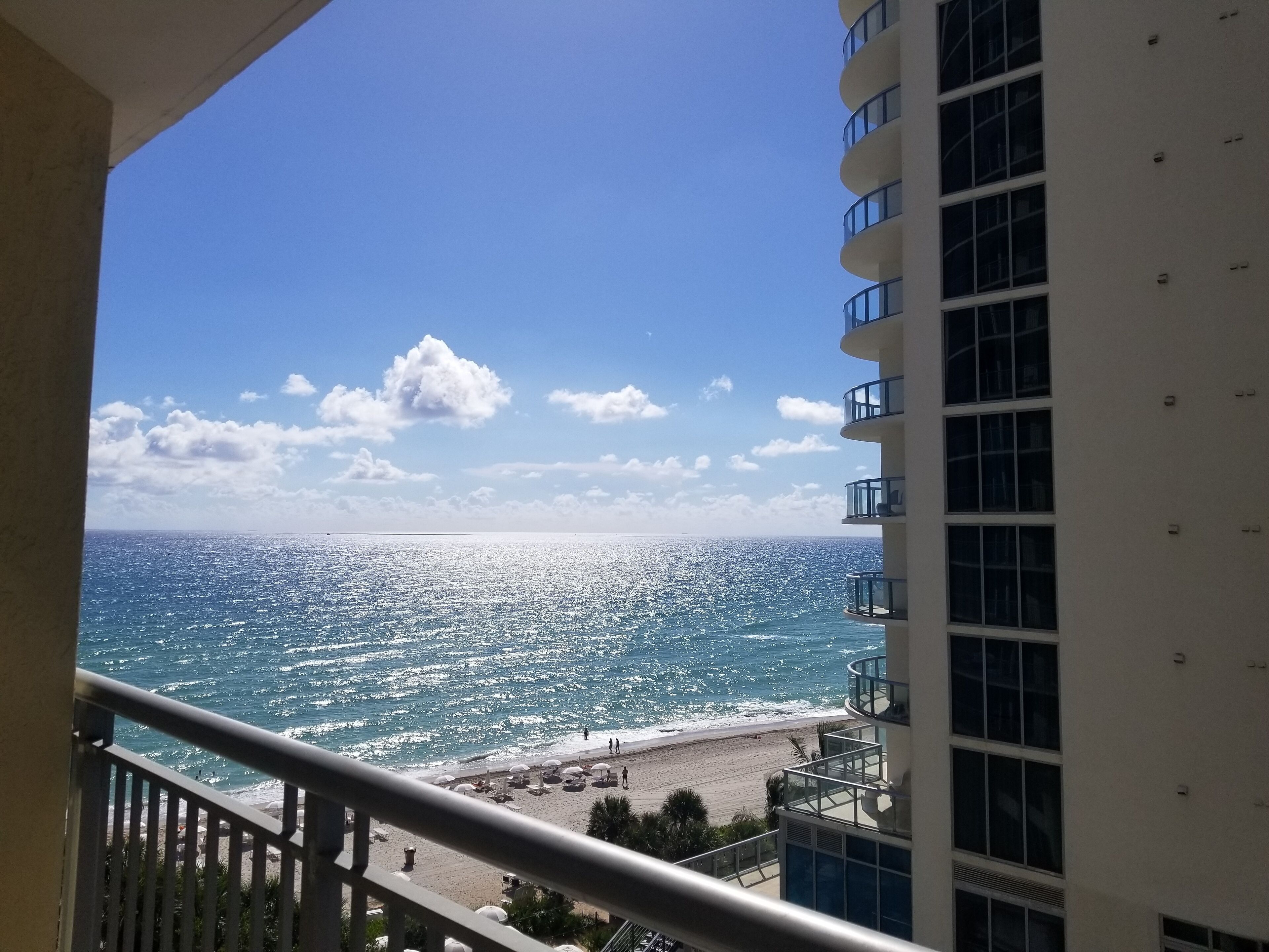Un balcon avec vue sur une plage et l’océan.