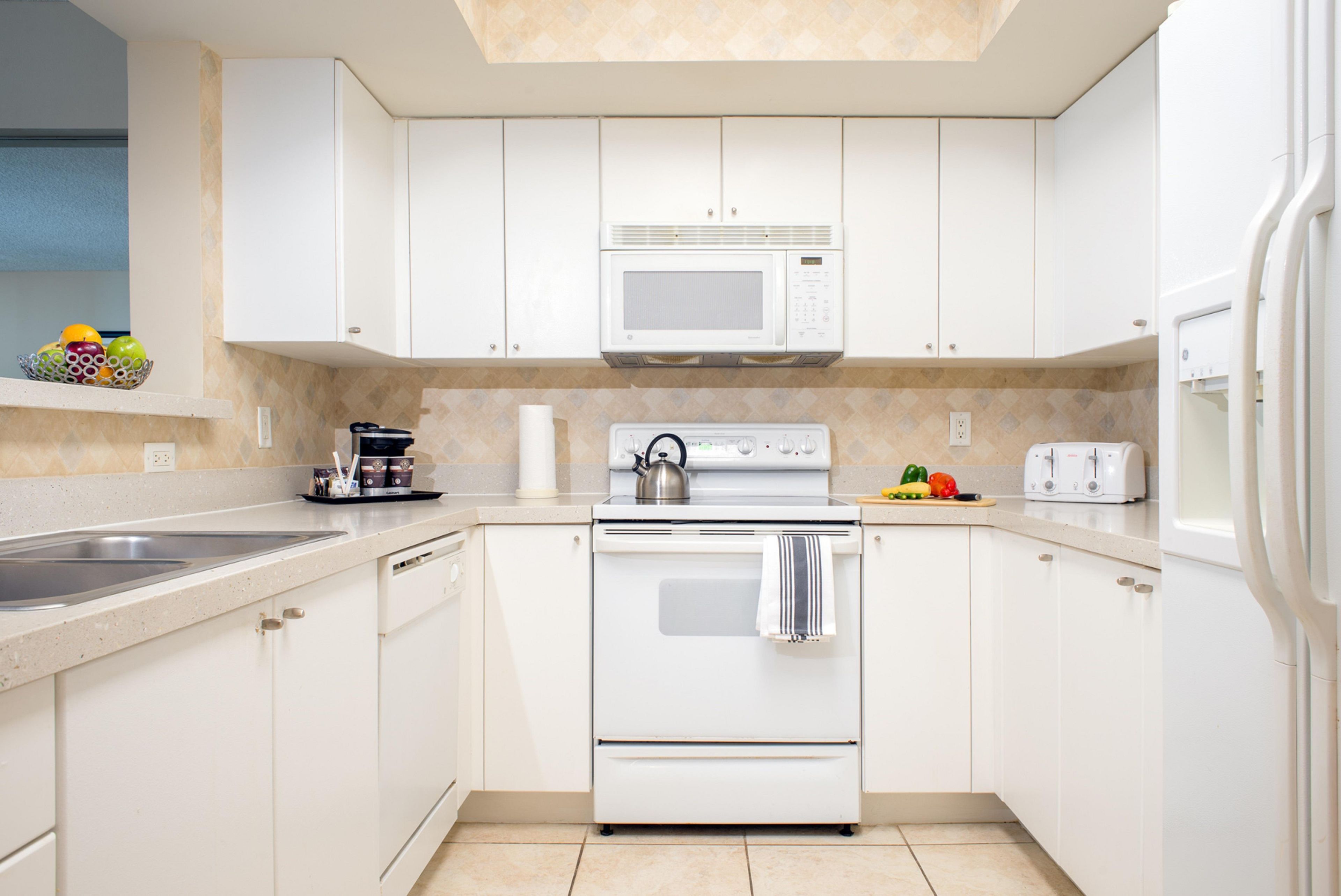 A modern kitchen with white cabinets, a built-in microwave, a stove, and a toaster.