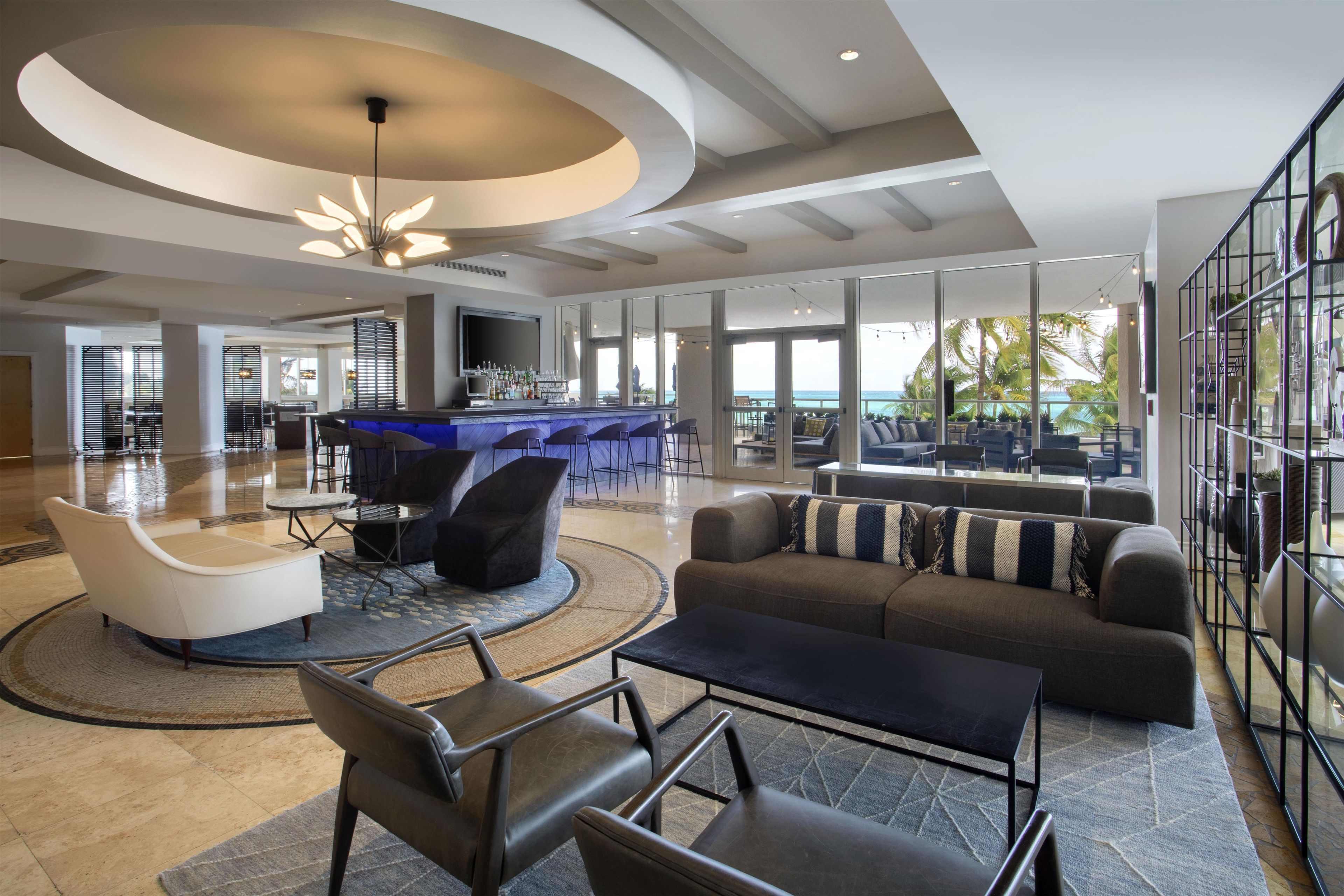 A spacious lobby with a bar area, seating arrangements, and large windows offering a view of the outdoors.